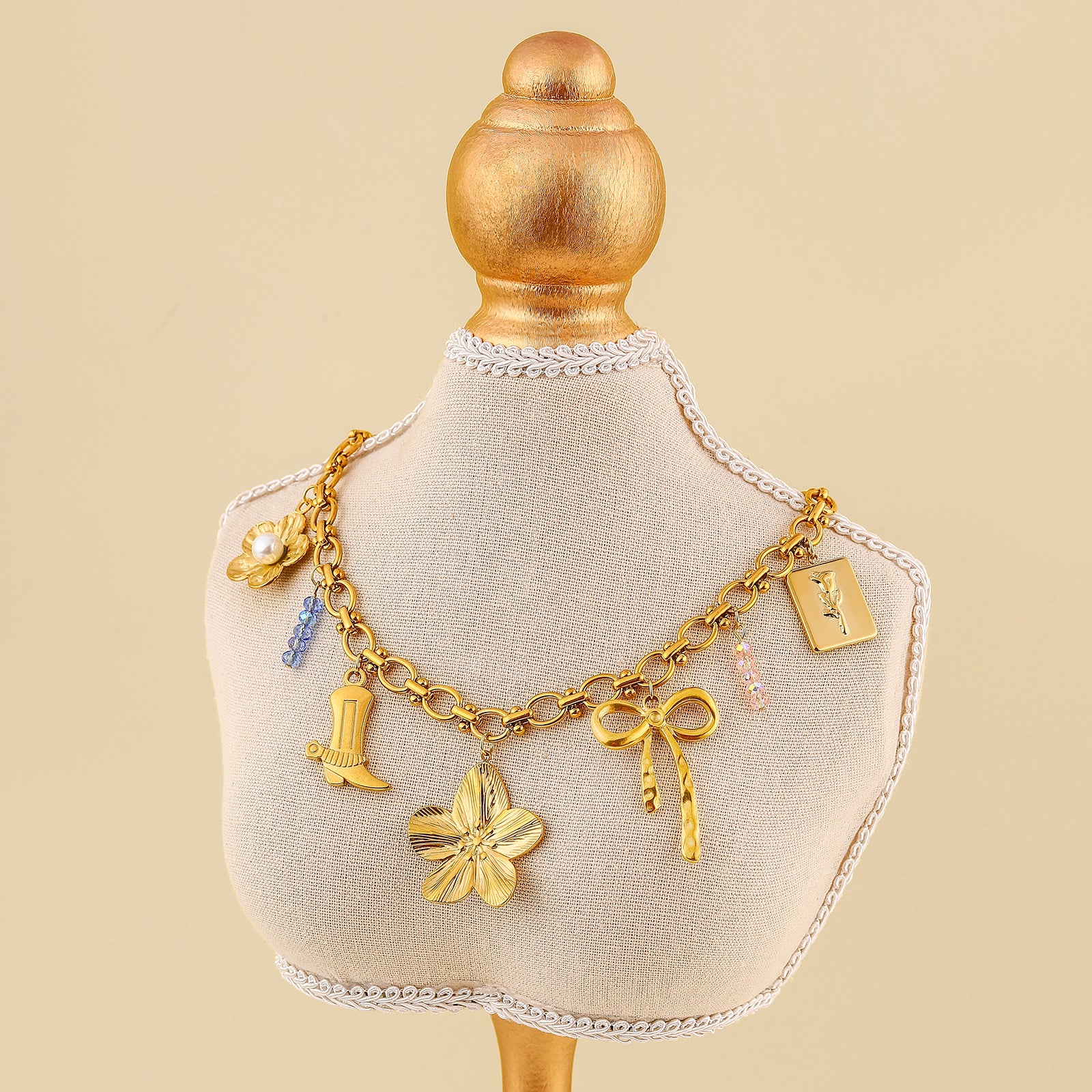 Gold charm bracelet on a mannequin bust with a beige background